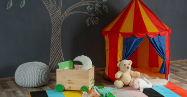 Colorful round kids rug in a bright playroom with toys and a reading nook, designed for easy cleaning and comfort