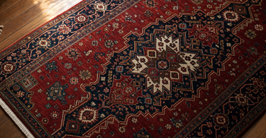 How to clean a Persian rug - close-up of a hand-knotted red and navy Persian rug on hardwood floor