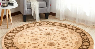 Person measuring the diameter of a round rug in a bright living room with a measuring tape