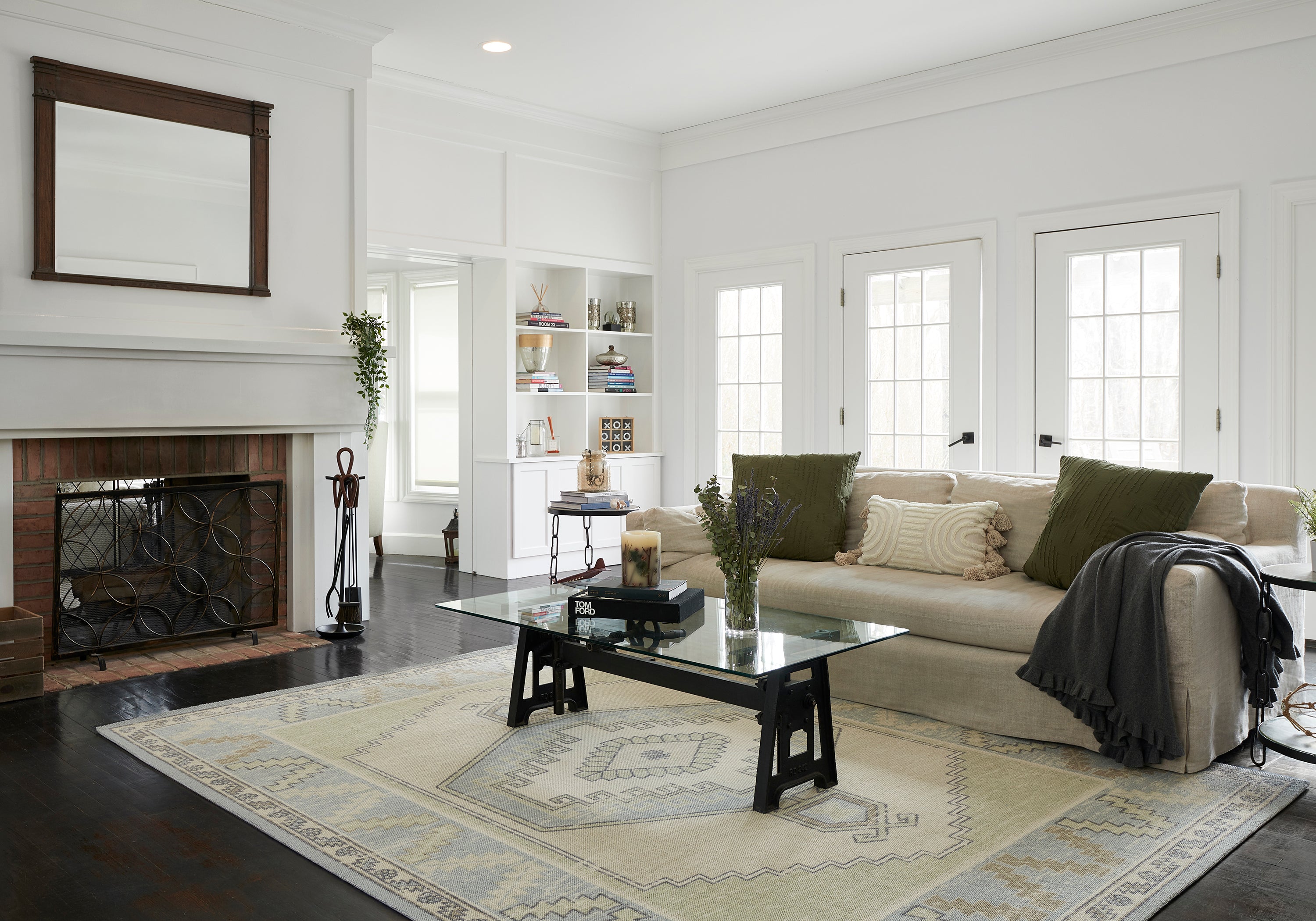 Living room with a light blue and cream Momeni Anatolia medallion rug under a glass coffee table, with a linen sofa and fireplace