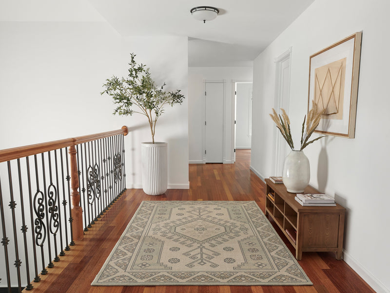 Sage and cream medallion rug on an upstairs landing beside a wood bench and a potted olive tree