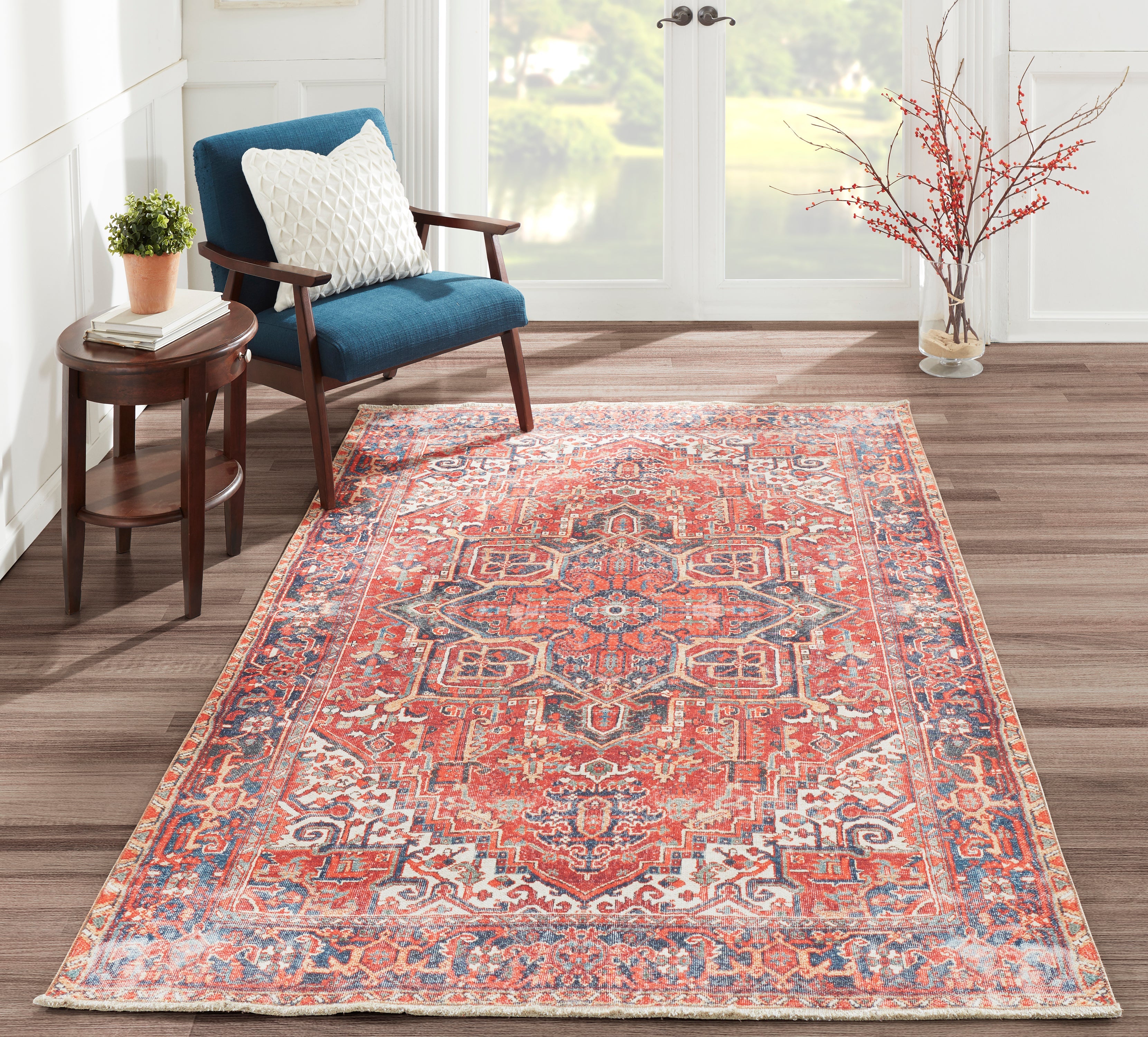 Red and navy Chandler medallion rug in a sunlit reading corner with a blue armchair and small side table