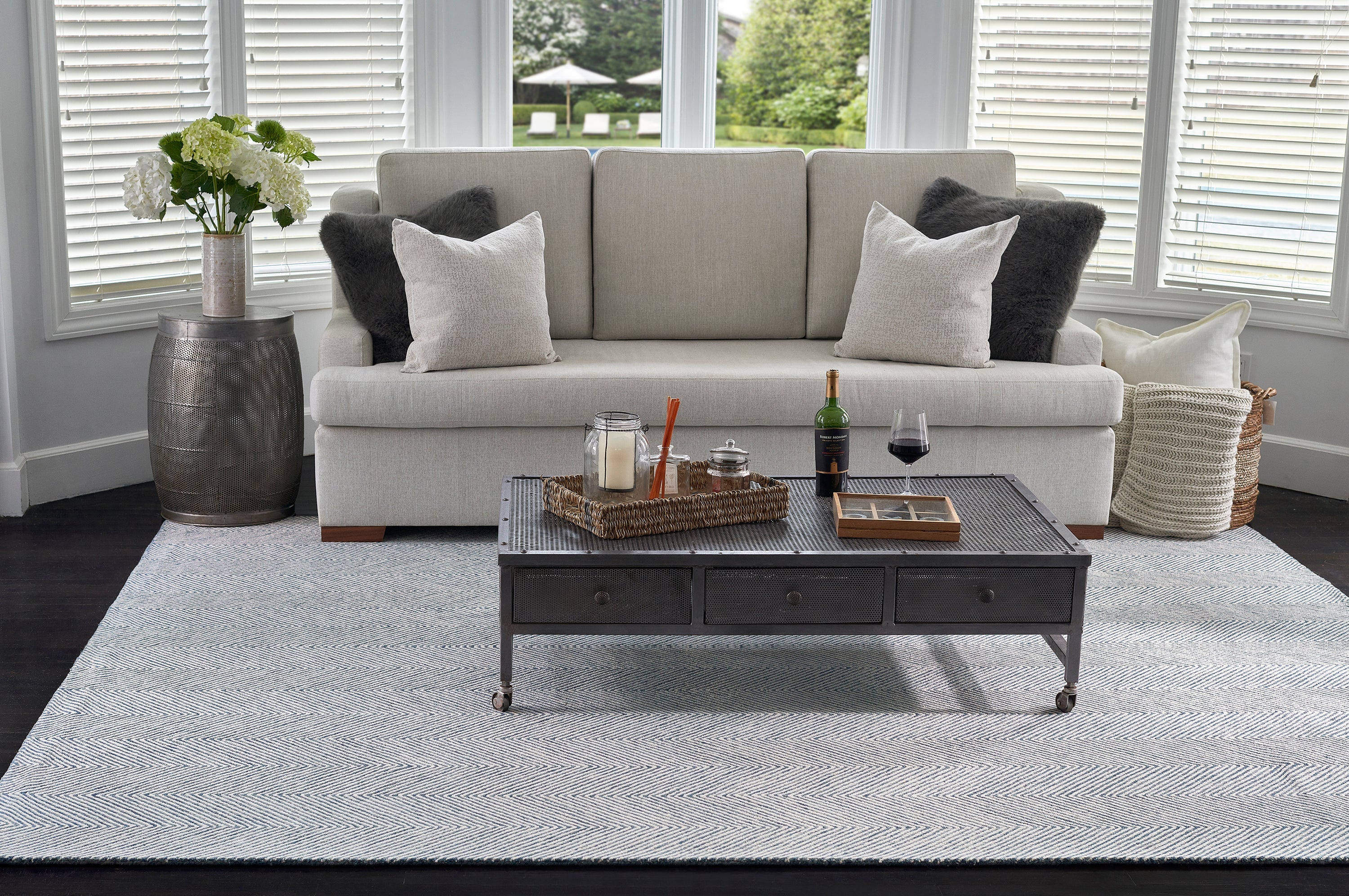 Light grey 8x10 wool rug under a sofa and dark coffee table in a bright living room