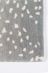 Hand-tufted blue wool rug with antelope spots on hardwood flooring
